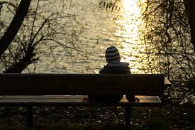 boy alone sitting bench sunset