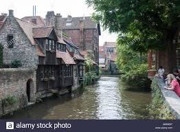 Tourists Taking In The Sight Of A Canal In Bruge Belgium Stock