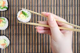 Une Main Avec Des Baguettes Tient Un Rouleau De Sushi Sur Un Fond De Tapis  De Serwing En Paille De Bambou | Photo Premium