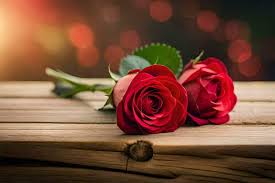 two red roses on a wooden table with a