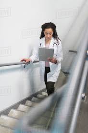 High Angle View Of Mixed Race Doctor Reading Medical Chart On Staircase Stock Photo