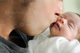 father kissing his newborn baby
