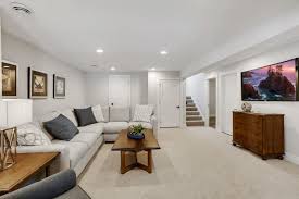 Neutral Basement Features A Sectional And Wood Accents