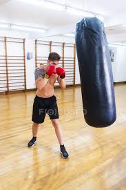 young guy boxing punch bag in a gym
