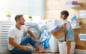 a dad and daughter putting clothes in washing machine