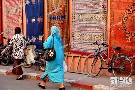 veiled women walking past berber rugs