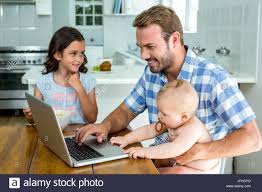 Happy Father Using Laptop While Taking Care Of Children