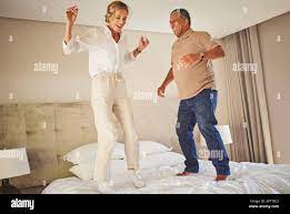 Senior interracial couple jumping on a hotel bed and having fun together.  Senior man and woman full of energy and life. They are celebrating and  enjoy Stock Photo - Alamy
