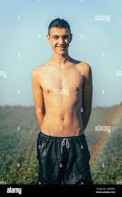Shirtless teenage boy enjoying sprinkler in farm against clear sky Stock  Photo - Alamy