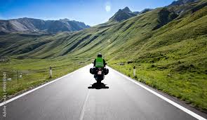 Motorradfahrer fährt mit seinem Motorrad auf kurvigen Straßen durch die Berge und einer wunderschöne Landschaft Stock-Foto | Adobe Stock