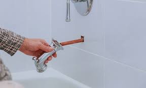 A Person Removes A Bathtub Faucet Spout