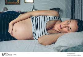 Schwangere Frau schläft im Bett - ein lizenzfreies Stock Foto von Photocase