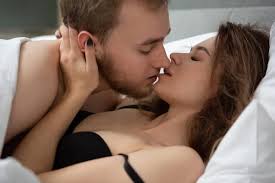 hot kiss of a young couple lying in bed