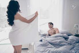 A Woman In White Towel Flashing Her Body To Her Husband Lying On The Bed.  Side View Stock Photo, Picture and Royalty Free Image. Image 115582224.