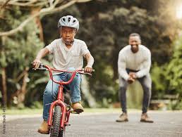 boy on bicycle father cheers and