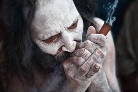 an ash smeared naga sadhu smoking pot