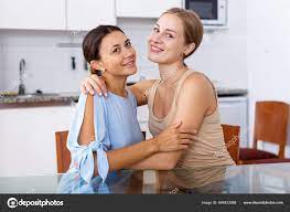 Young Smiling Emotional Girlfriends Sharing Secrets Sitting Table Home  Stock Photo by ©Jim_Filim 644433068