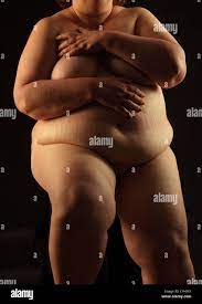 Obese naked woman seated on a black background Stock Photo - Alamy