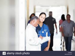 Doctor And Nurse Reading Medical Chart In Hospital Hallway