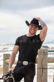 hot rugged cowboy by a rustic fence