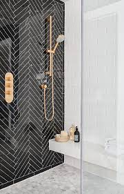 The faucet is mounted beneath a round mirror hung from a white and black wallpaper wall. 11 Bathrooms With Black Herringbone Tiles