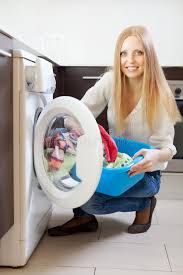a lady squating about to put clothes in a washing machine