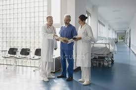 Doctors Discussing Medical Chart In Hospital Corridor Lab