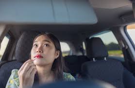 young woman applying makeup while driving