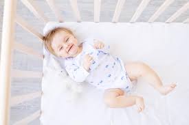 laughing baby blond boy lies in a crib