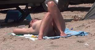 Atemberaubende nackte Frau genießt Sonne am FKK-Strand