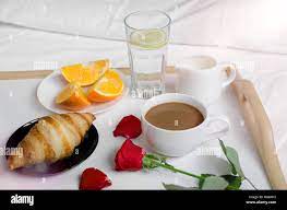 Saint Valentin romantique petit-déjeuner au lit, plateau avec croissant,  tasse de café espresso avec du lait, les oranges fraîches, verre d'eau avec  du citron et rose rouge Photo Stock - Alamy