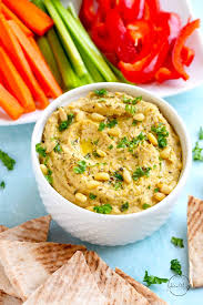 roasted garlic hummus with pine nuts and parsley on top and veggies in the background