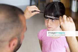 father cutting daughter s hair at home