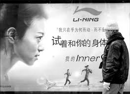 A pedestrian walks past a Li-Ning advertisement in Beijing. The company plans to consolidate inefficient outlets and add a net 600 stores next year, ... - 002564baf2f90e5152ac07