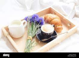 De l'été romantique petit-déjeuner au lit, plateau avec croissant frais,  tasse de café espresso avec lait et bouquet de bleuets bleu. Bon matin  concept. E Photo Stock - Alamy