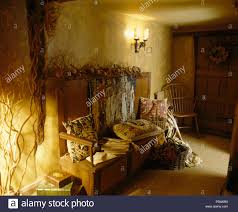 Tapestry Cushions Piled On Old Wooden Settle In Country Hall