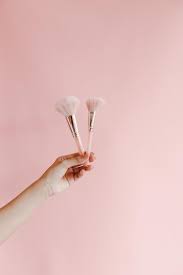 women hands hold pink brushes