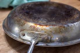 How can you restore the appearance of stainless steel pans?