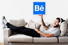 Male Holding A Behance Icon On The Couch