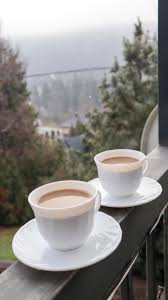 two coffee cups on a balcony with