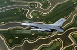 An F-16 Fighting Falcon aircraft flies over a golf course on ...