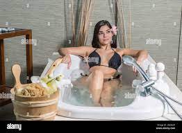 Sensual young brunette in bikini lying in recreation bath enjoying massage  center Stock Photo - Alamy