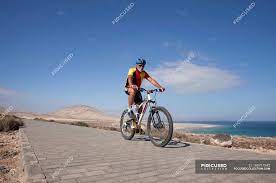 man on mounn bike riding on pavement