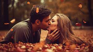 couple kissing in leaves in the forest