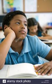 Male Elementary School Student Daydreaming In Class Stock Photo