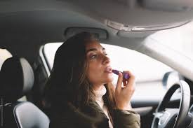 young woman putting makeup in her car