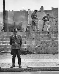 the building of the berlin wall history berlin wall a west berlin guard stands in front of the concrete wall dividing east and west berlin at bernauer strasse as east berlin workmen add blocks to the wall to