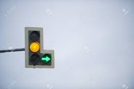 Traffic Light With Yellow Light And Green Arrow On The Background