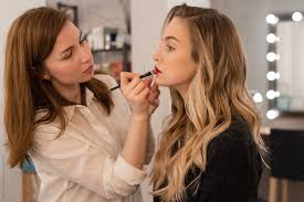 makeup artist rouging lips of young