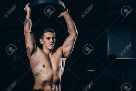 バーベルの重さを保持しているエンボス加工の筋肉を持つ上半身裸の若いスポーツマン の写真素材・画像素材. Image 103198661.
